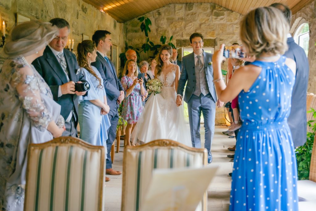 Hochzeitsfeier mit der Braut, Gästen und festlicher Dekoration in einem rustikalen Raum.