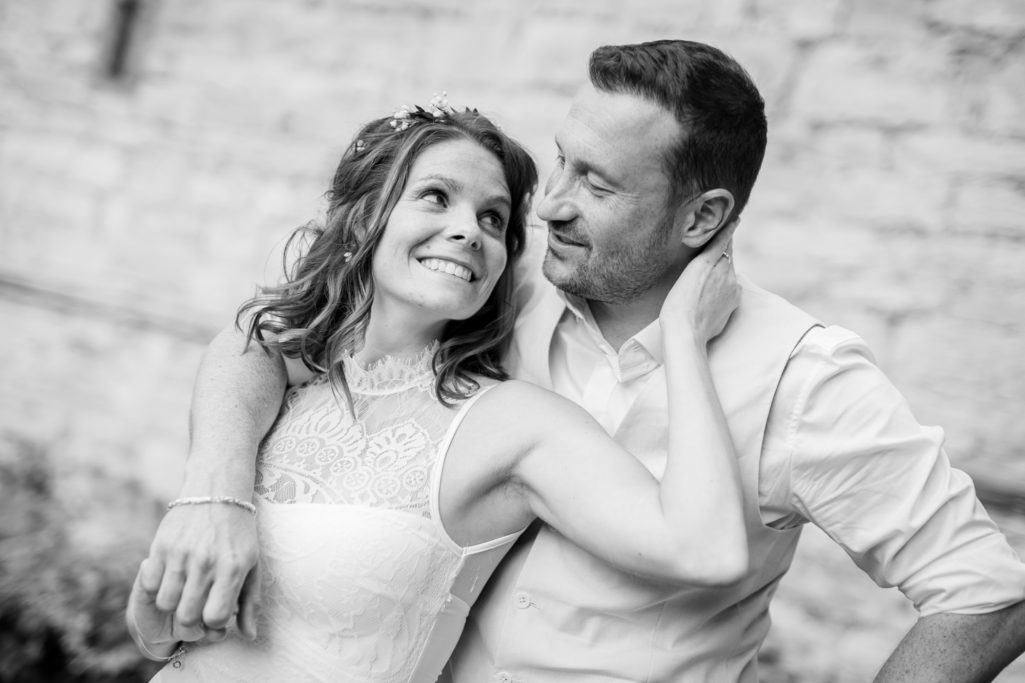 Braut und Bräutigam lächeln einander in einer romantischen Umarmung an.