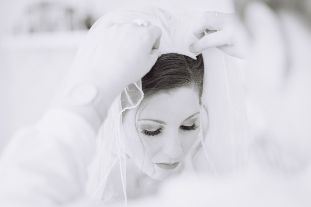 Braut mit Schleier, konzentriert und in stiller Vorbereitung auf den besonderen Tag.