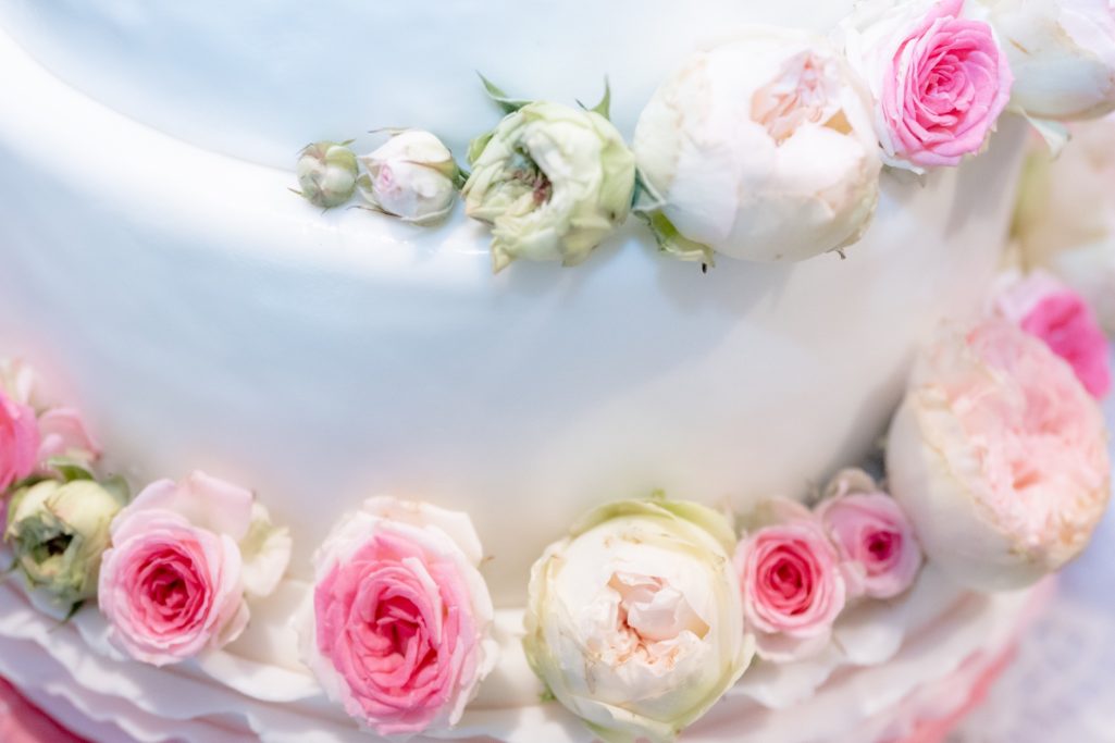 Hochzeitstorte mit weißen und rosanen Rosenverzierungen.