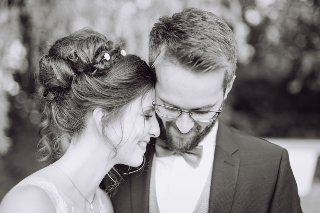 Ein Brautpaar lächelt sich liebevoll an, umgeben von einer festlichen Kulisse.