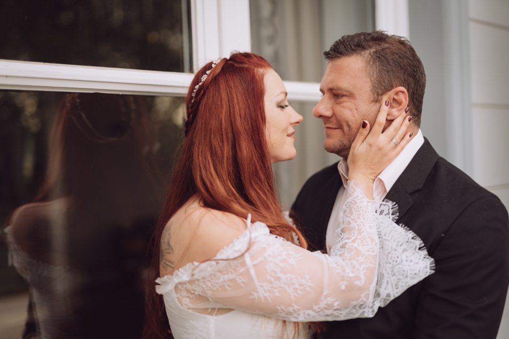 Brautpaar blickt sich liebevoll in die Augen, während sie sich zärtlich berühren.