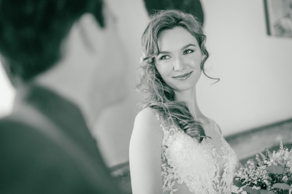 Braut in elegantem Kleid schaut lächelnd auf ihren Partner. Romantische Atmosphäre.